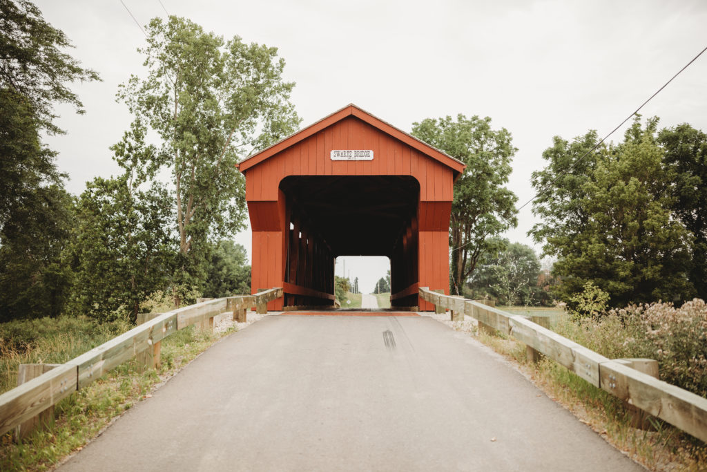 Front view of the Swartz Covered Bridge with the road leading up to it, through it, and behind it.