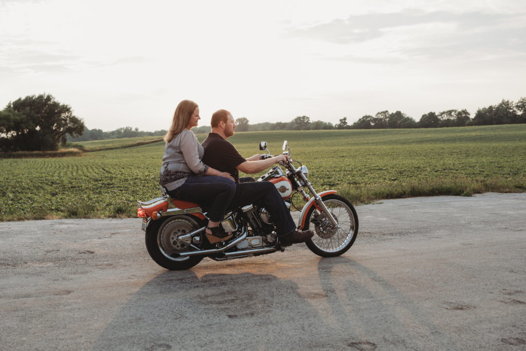 Brandon and Rachel ride his motorcycle as the sun hides behind their heads.