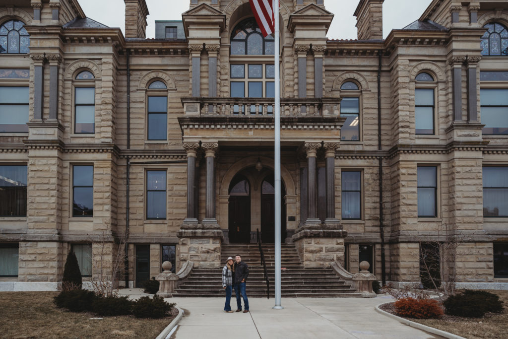Couple stands in front of the Common Pleas Courthouse in downtown Findlay for their engagement session.